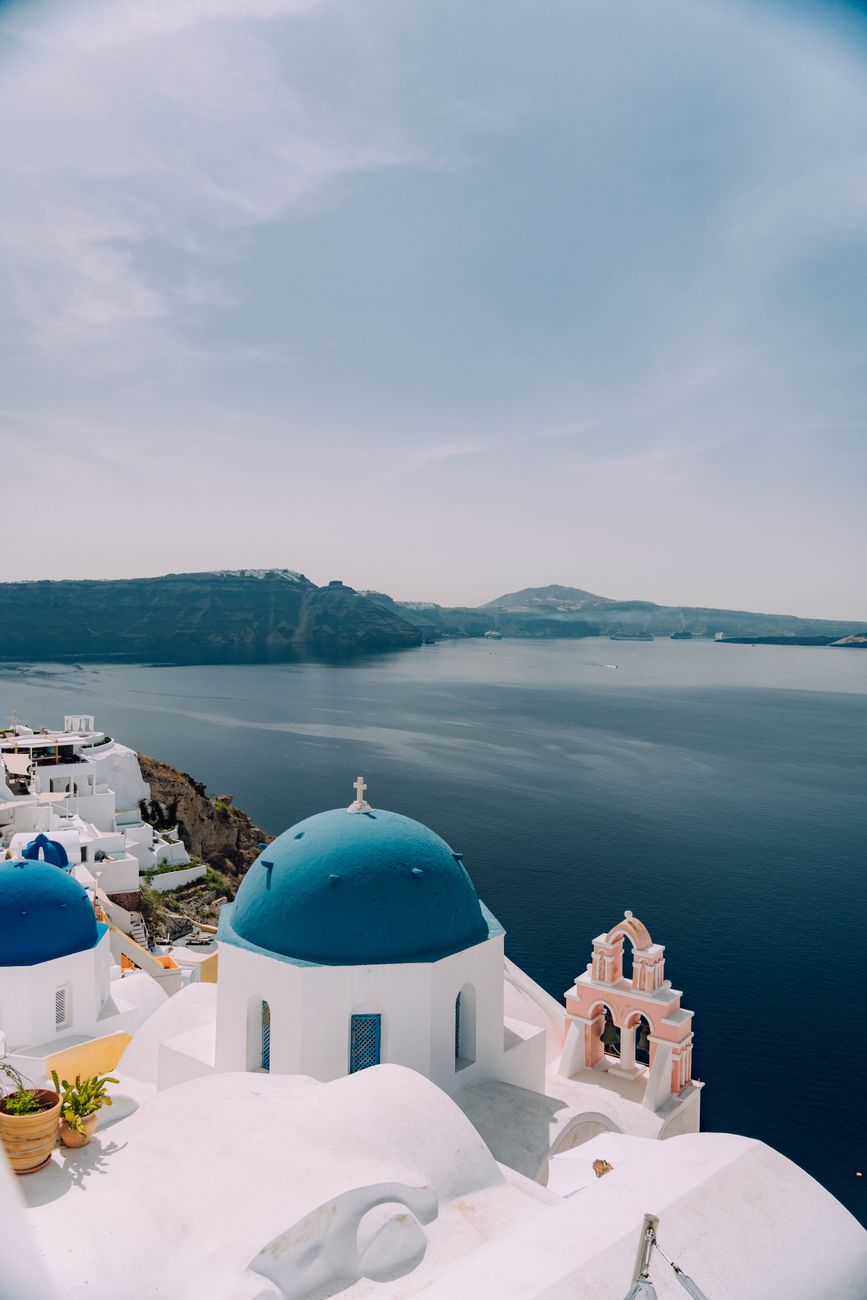 Santorini white houses and blue domes above the caldera at golden hour — classic Greek island aesthetic