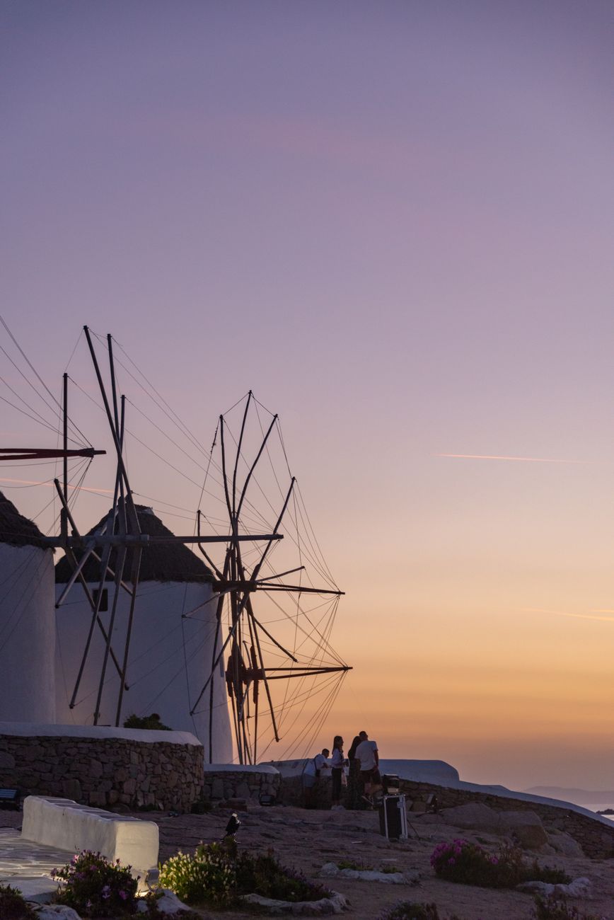 The iconic Mykonos windmills in a row above the Aegean sea at sunset